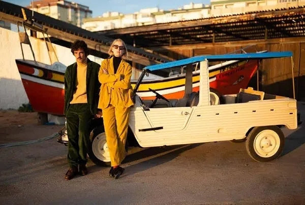 Homecore Fotoshooting - ein Paar in Retro Cord Anzügen vor einem offenen Auto
